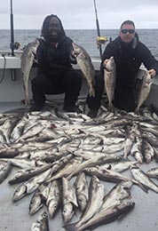 2 men amoung large amount of caught cod fish on boat