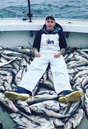 Man sitting on boat desk with large amount of cod fish